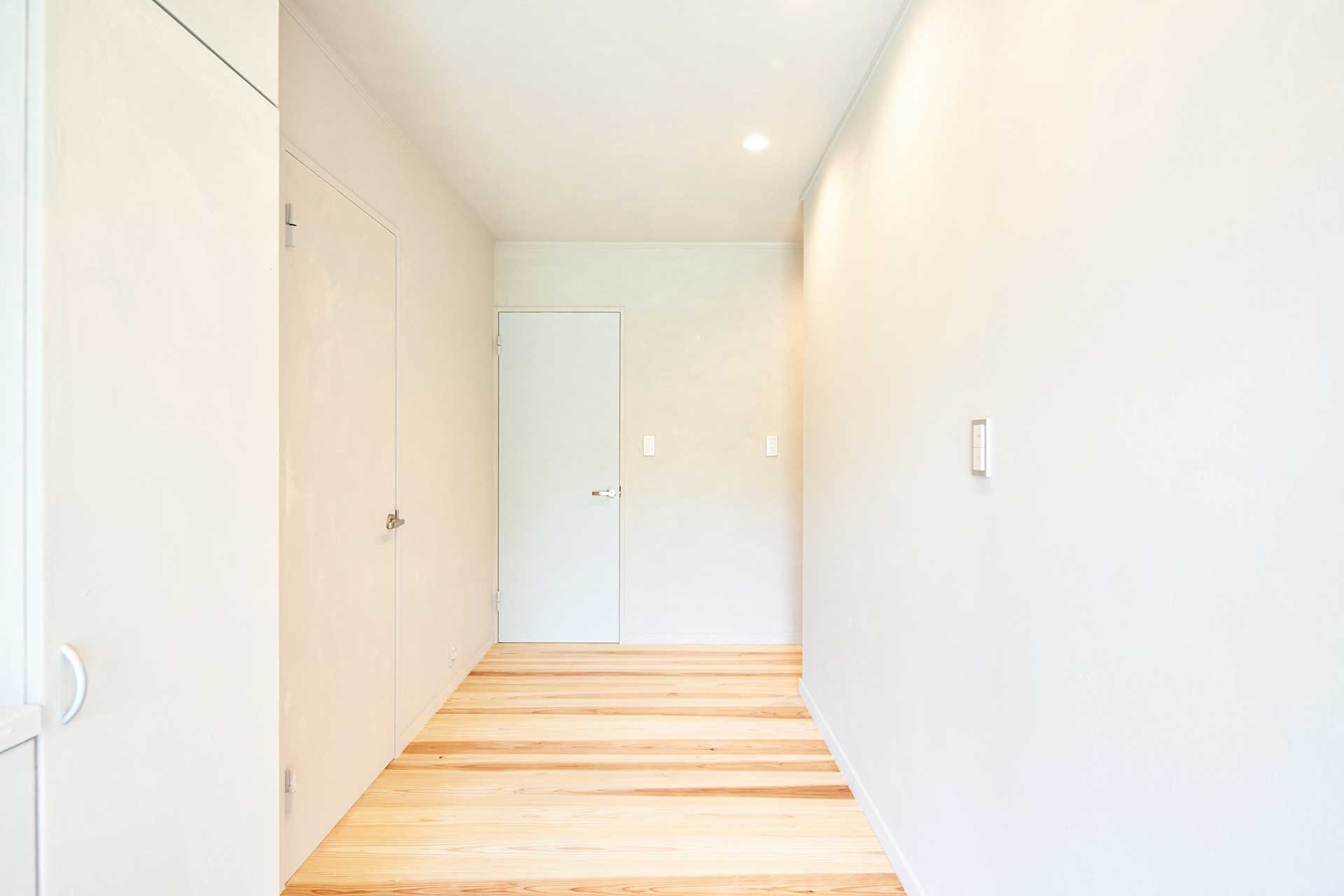 秋田杉の無垢床材と色数を抑えた壁面で、明るくシンプルにまとめた玄関。
